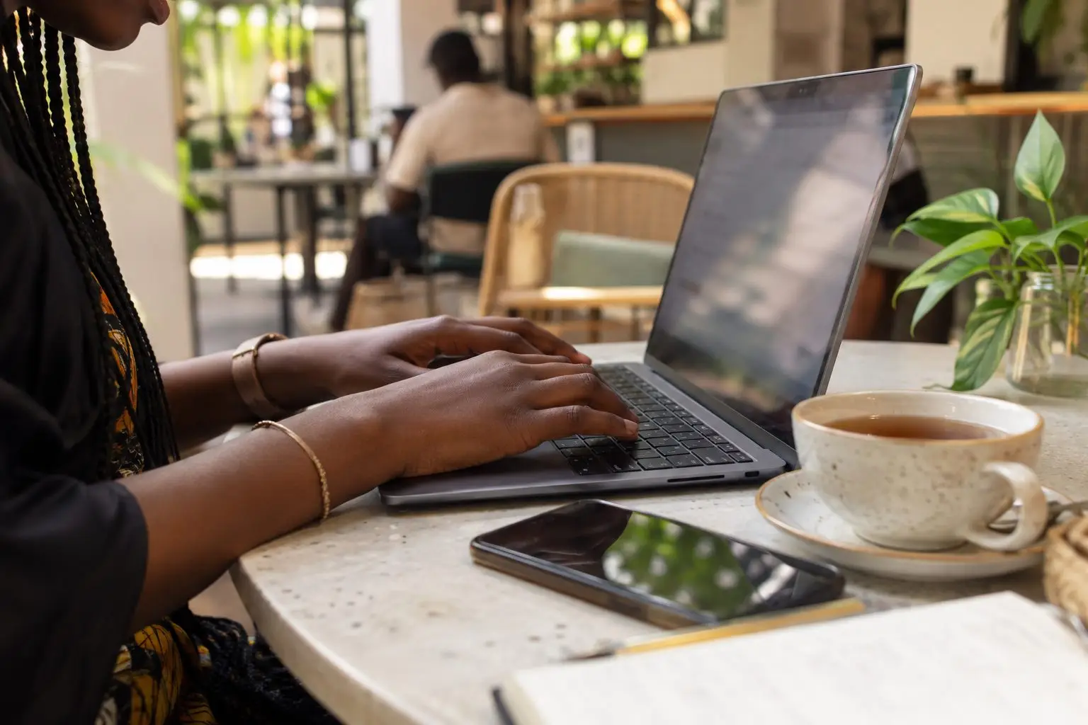 Hands typing on a laptop at a cafe table